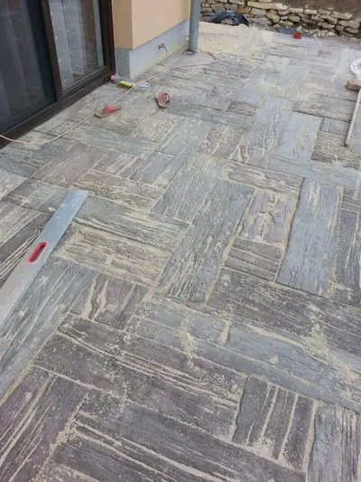 Terasa z betonové dlažby imitující dřevěná prkna, na ní vodováha