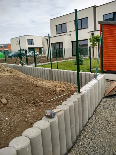 Obruba z palisád a sloupky panelového plotu u řadových domů