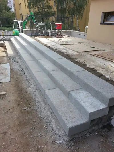 Široké schody ze šedých betonových prvků podél domu