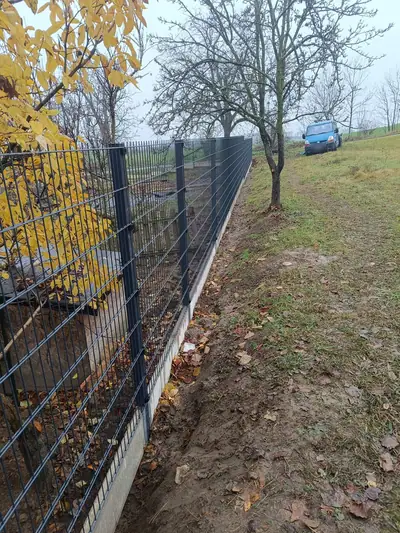 Tmavý panelový plot s podhrabovými deskami ve svahu