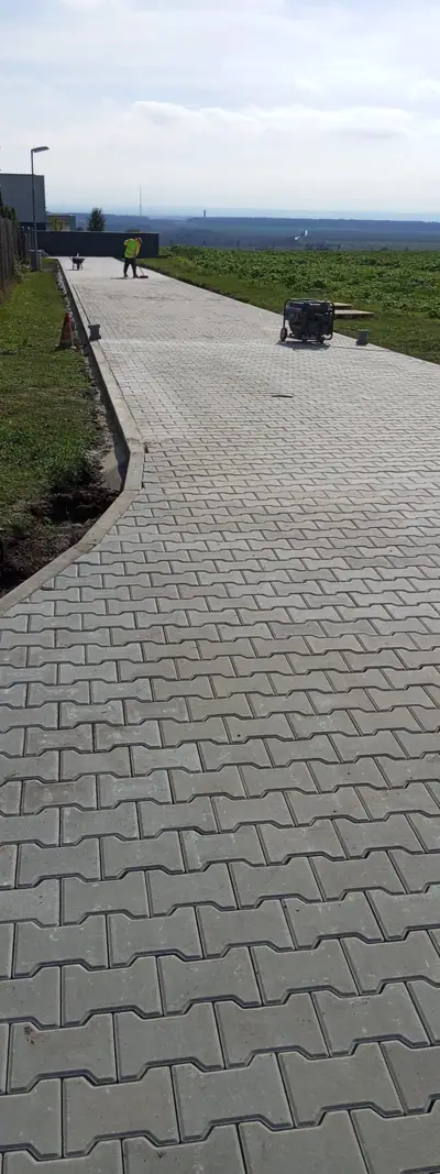Dlouhá cesta ze zámkové dlažby tvaru I s výhledem do krajiny
